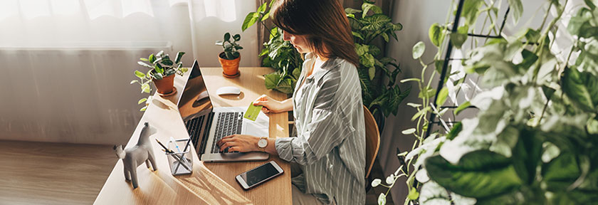 mobile photo of a woman at home office desk holding a credit card, June 2024, TCU